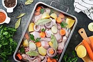 Cooking chicken bouillon or roast in cooking pan or pot with vegetables potatoes, carrots and herbs on kitchen grey concrete