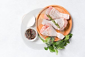 Cooking chicken drumsticks with seasonings and spices on wooden plate over white table background