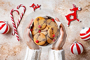 Cooking Christmas gingerbread. Woman`s hands holding red nosed reindeer cookies box. Festive homemade decorated sweets