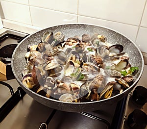 Cooking clams in a stone pan using parsley and white wine