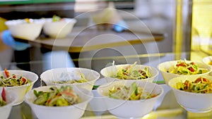 Cooking. close-up. waiter, in protective gloves, puts bowls of salads to self-service food display showcase. Cuisine