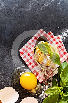 Cooking concept. Ingredients for traditional Italian homemade pasta tomatoes  raw egg  basil leaf on the dark concrete background