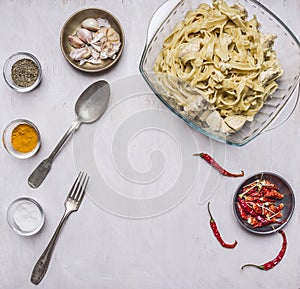 Cooking concept ready-made pasta with turkey in cream sauce with garlic, red chili peppers fork spoon spices in glass bowls on
