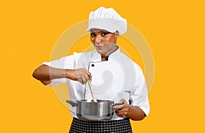 Cooking Concept. Smiling Black Chef Woman Stirring Food In Saucepan