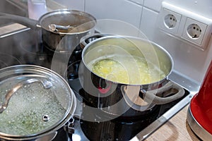 Cooking on cooker in the kitchen with hot steam and pots on a ceran stove to cook delicious meals for the family photo