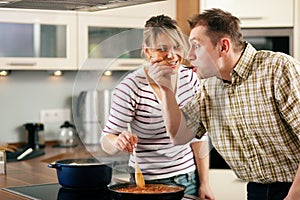 Cooking couple - tasting the sauce