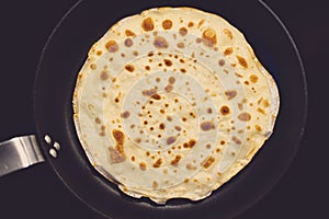 Cooking of crepe or thin pancake in a frying pan. Top view
