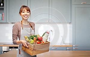 happy woman in apron with food in wooden box