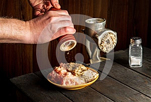 Cooking cutlets with the hands of a chef on a dark background. Add pepper to the minced meat. Free space for restaurant