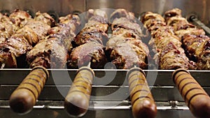 Cooking delicious meat skewers on skewers with wooden handles. Street eatery. Grilled food. Automatic rotation of skewers. B-B-Q.