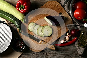 Cooking delicious ratatouille. Different fresh vegetables, spices and knife on wooden table, flat lay