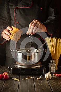 Cooking delicious soup for lunch. Working environment in the kitchen. The chef adds salt to the stock pot. Cucina italiana photo