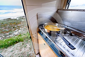 Cooking dinner or breakfast in camper motorhome with beach view.