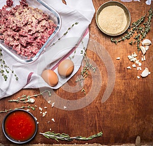 Cooking dish of raw meat with breadcrumbs and eggs tomato sauce with garlic and herbs napkin rustic wooden background close u