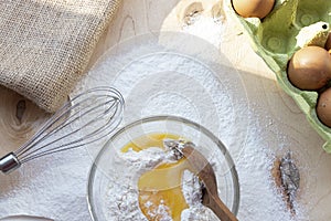 Cooking dough. A raw egg. Stir the protein with the yolk. Sifting flour through a sieve on a wooden background. Glass bowl with