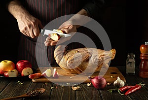 Cooking duck for lunch by the cook hands. Raw duck with apples and spices on the kitchen table. The chef cuts an apple