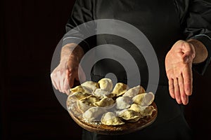Cooking dumplings in the kitchen of the restaurant by the hands of the chef. Presentation of dumplings on a cutting board.