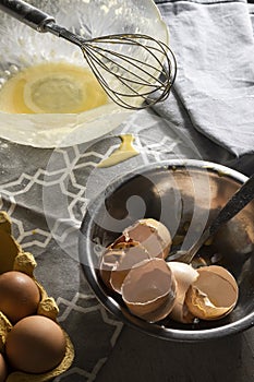 Cooking with eggs, cracked egg shells, used kitchen utensils on the table