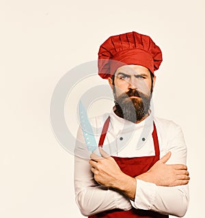 Cooking equipment and cuisine concept. Cook with serious face in burgundy apron and chef hat.