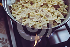 Cooking farfalle pasta on a burning gas hob