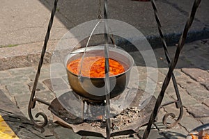 Cooking in field conditions. Boiling pot with soup hanging over the campfire