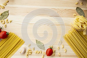 Cooking food background with free space for text. Composition with pasta, tomato, eggs, garlic, bay leaf over the wood background