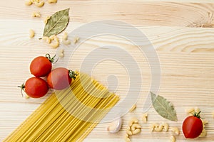 Cooking food background with free space for text. Composition with pasta, tomato, eggs, garlic, bay leaf over the wood background