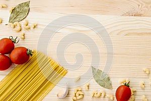 Cooking food background with free space for text. Composition with pasta, tomato, eggs, garlic, bay leaf over the wood background