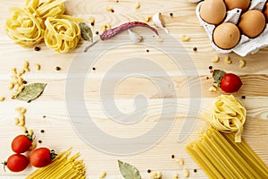 Cooking food background with free space for text. Composition with pasta, tomato, eggs, garlic, bay leaf over the wood background