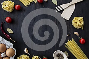 Cooking food background with free space for text. Composition with spaghetti, tomato, eggs, garlic, bay leaf over the wood