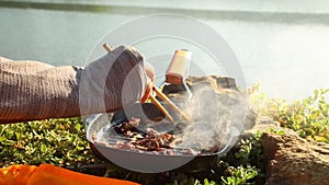 Cooking food during camping outdoors near the lake in the morning