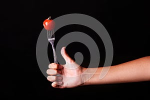 female hand with fork and tomato