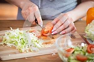 Cooking, food and concept of veganism, vigor and healthy eating - close up of female hand cutting vegetables for salad