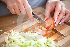 Cooking, food and concept of veganism, vigor and healthy eating - close up of female hand cutting vegetables for salad