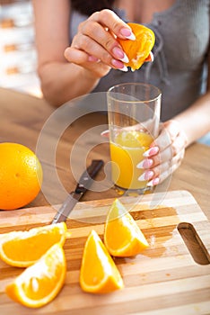 Cooking, food and concept of veganism, vigor and healthy eating - close up of female hand squeeze fresh orange juice