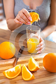 Cooking, food and concept of veganism, vigor and healthy eating - close up of female hand squeeze fresh orange juice