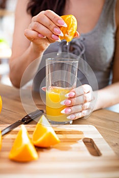 Cooking, food and concept of veganism, vigor and healthy eating - close up of female hand squeeze fresh orange juice