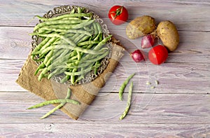Green beans and vegetables on a wooden background