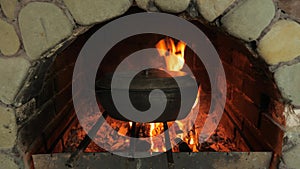 Cooking food in the oven on an open fire. Cast-iron cauldrons with food. Firewood and fire in the oven. Rustic food on