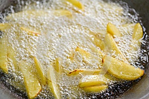 Cooking french fries or fry potatoes in hot oil for potato wedges, Close up fried potatoes in oil on pan