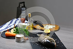 Cooking fresh fish carp, baking with Vegetables, lemon, herbs and spices on wooden table flat top view, copy text menu