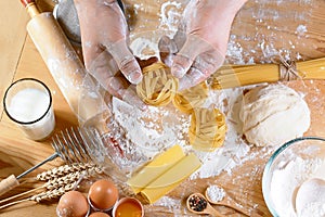 Cooking fresh italian uncooked homemade pasta tagliatelle at wooden table, in the hands of the chef, set