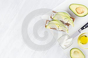 Cooking of fresh light summer appetizer of crisps bread, avocado slices, olive oil, black sesame seeds, cream cheese.