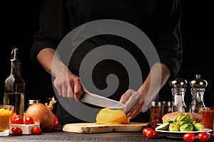 Cooking fresh salad, the chef cuts the paprika on the background of vegetables. Vegetables and healthy eating