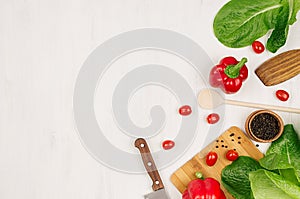 Cooking fresh spring salad of green and red vegetables, spices on white wooden background, border, top view.