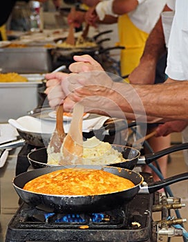 Cooking frico, the typical Friulian dish made of heated cheese and potatoes.