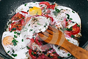 Cooking Fried eggs with tomatoes and onions in a pan