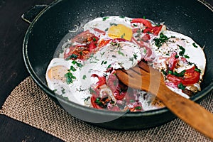 Cooking Fried eggs with tomatoes and onions in a pan