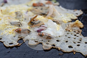 Cooking fried oyster omelet in big hot pan. Street restaurant in Thailand, closeup