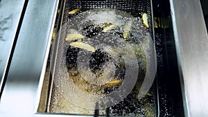 Cooking and frying french fries in oil. Boiling deep fat in a large bowl on the stove in a restaurant.